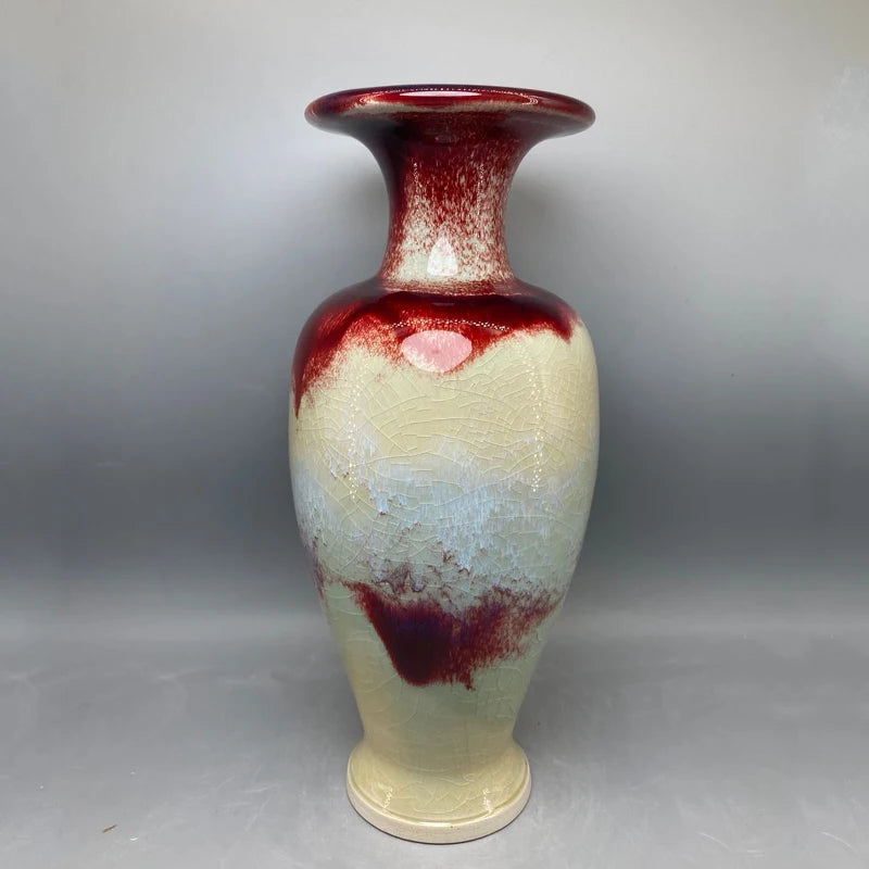 Le vase décoratif en céramique présente des couleurs rouges et blanches créant un motif élégant et texturé.