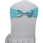 Chaise blanche avec un noeud en satin bleu turquoise décoratif et une ceinture accroché autour.