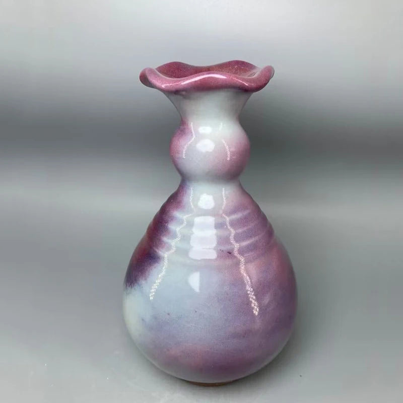 Un vase artisanal en céramique de couleurs pastel rose et gris, au design moderne et élégant.