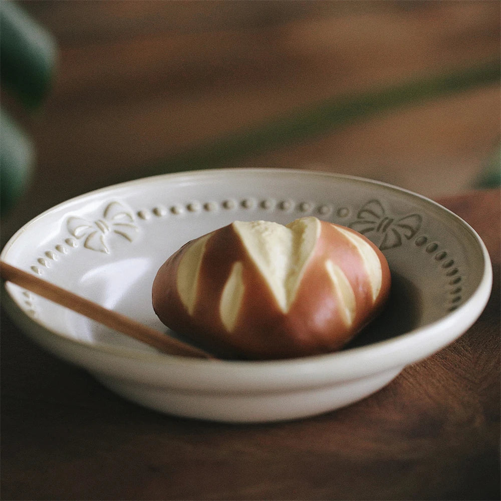 Sur une assiette blanche décorée, se trouve une pomme fraîche, avec une belle peau brillante et une couleur rouge vif.