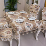 Cette image présente une table de salle à manger élégante recouverte d'une nappe à motifs floraux et ornée de coussins assortis, dans un style vintage et raffiné.