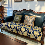 Ce canapé vintage en cuir noir avec ses coussins décoratifs aux motifs floraux dorés et foncés offre une élégance classique qui s'intègre parfaitement dans un intérieur sophistiqué.