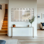 Intérieur spacieux et lumineux avec un escalier en bois, un miroir décoratif et un meuble console sobre.