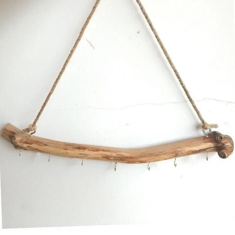 Branche suspendue en bois flotté naturel accrochée au mur avec crochets métalliques