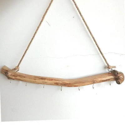 Branche suspendue en bois flotté naturel accrochée au mur avec crochets métalliques