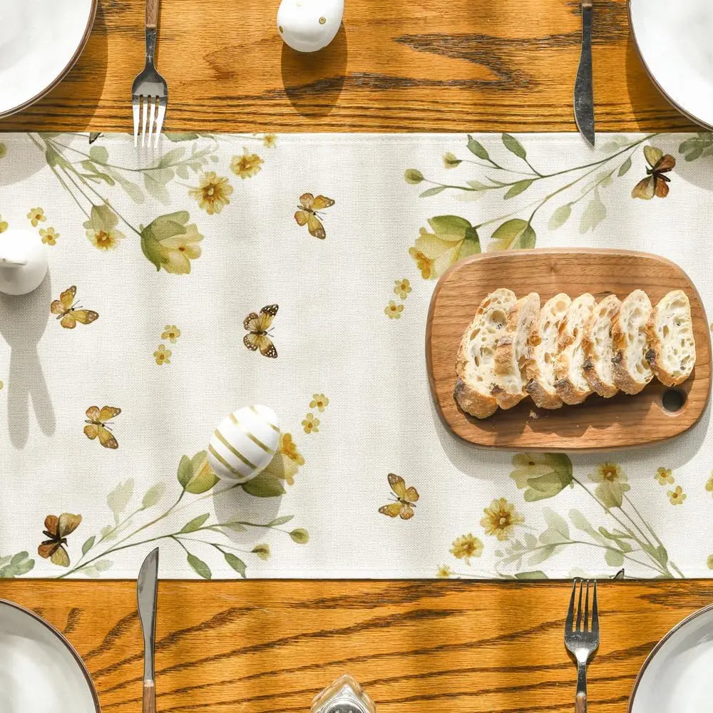 Une vue de dessus sur une table avec un plateau en bois, des ustensiles et une assiette de tranches de pain sur un fond fleuri.