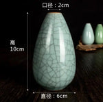 Vase décoratif en porcelaine blanche avec des motifs de craquelures, forme en goutte d'eau avec des dimensions de 10 cm de hauteur et 6 cm de largeur.