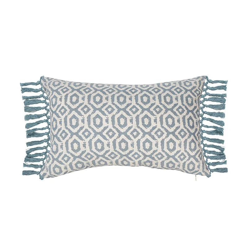 Coussin rectangulaire gris et blanc avec motif géométrique et franges sur les côtés.