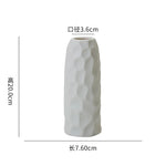 Vase céramique blanc texturé avec un motif en relief, de forme allongée et cylindrique.