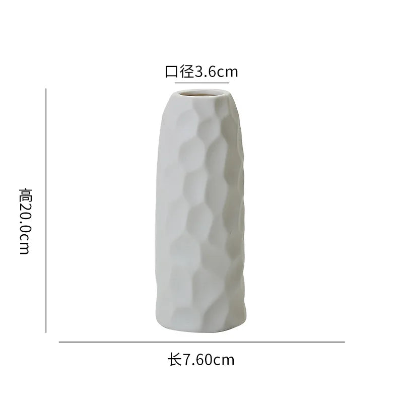 Vase céramique blanc texturé avec un motif en relief, de forme allongée et cylindrique.