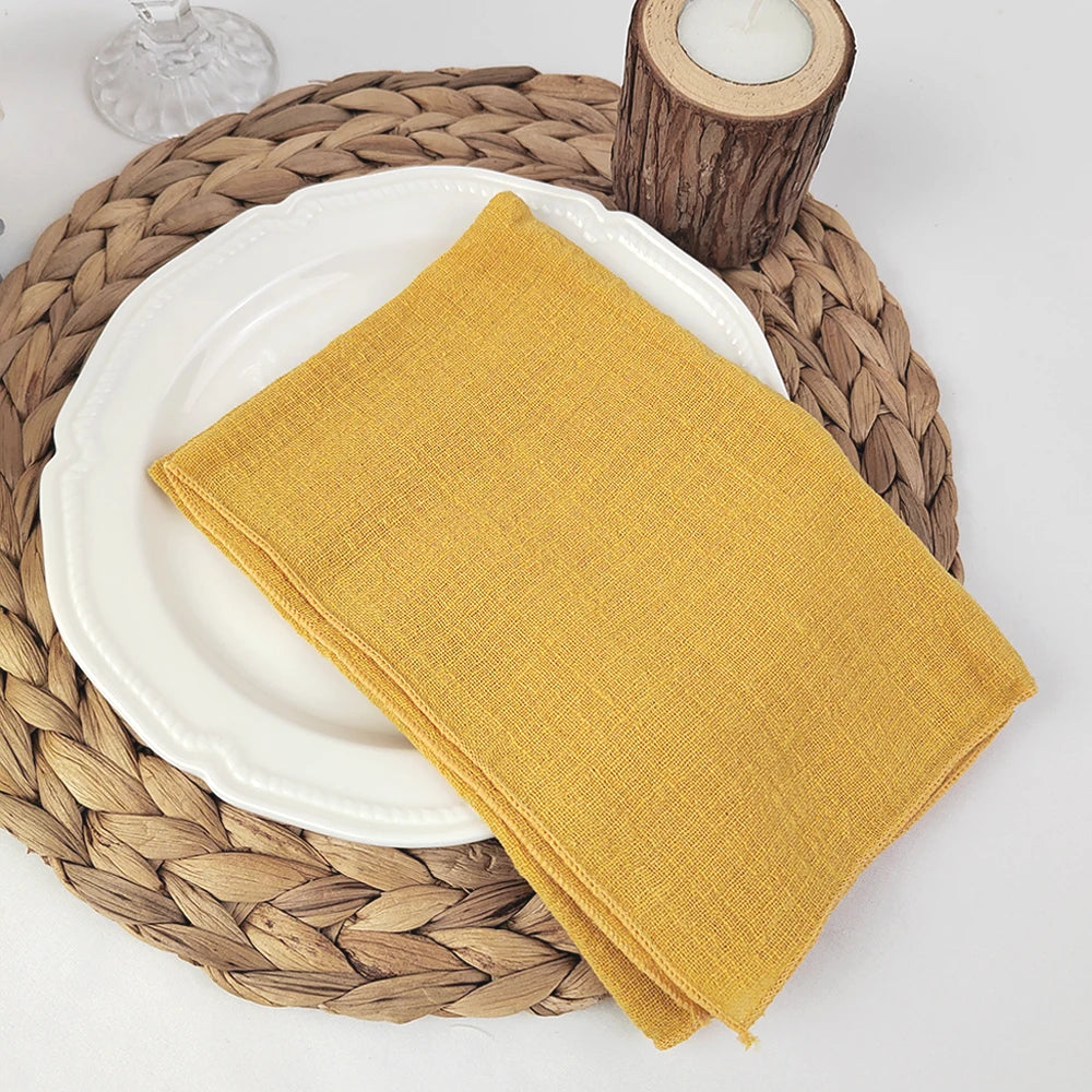 Une serviette de table jaune vif posée sur un plat blanc entouré d'un tapis en fibre naturelle et d'un bougeoir en bois.
