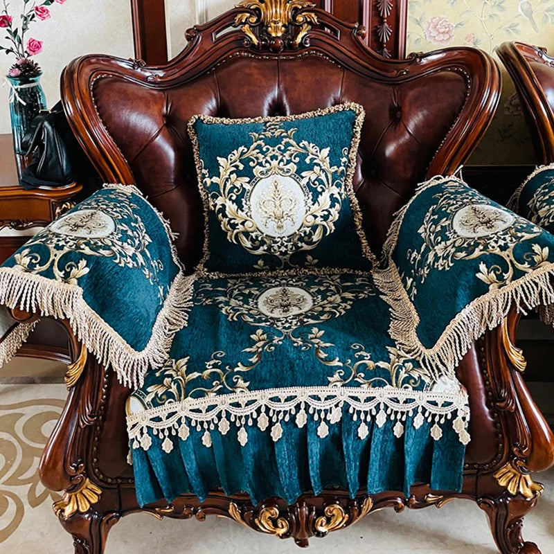 Le canapé en cuir brun foncé est orné de coussins décoratifs en velours bleu et or, avec des motifs floraux élégants et une frange luxueuse, créant une atmosphère raffinée et sophistiquée dans cette pièce d'intérieur.