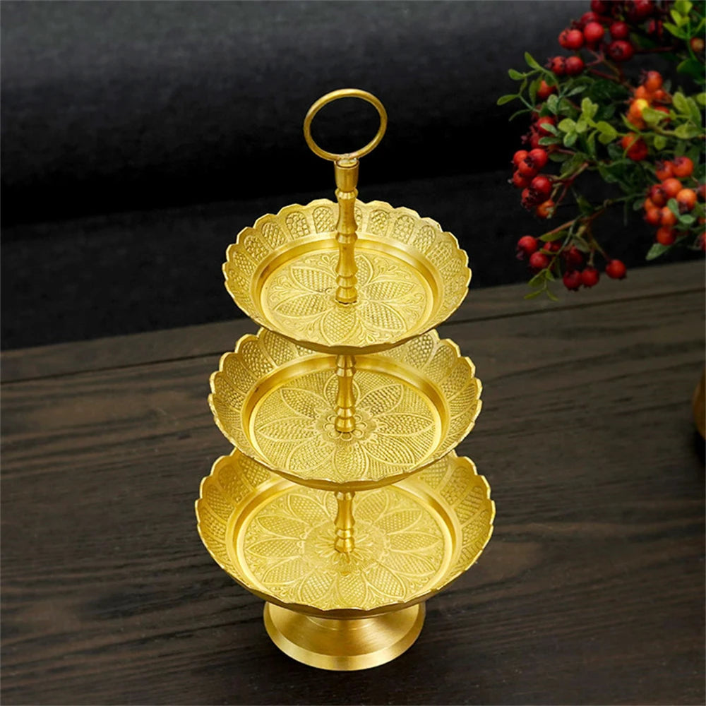 Présentoir doré à trois étages avec motifs floraux sculpturaux, servant de support élégant pour présenter des collations ou des desserts.