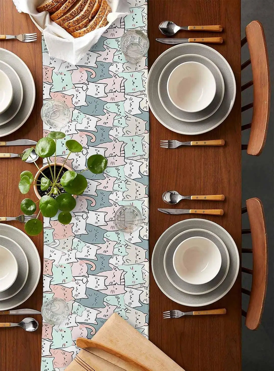 Une table joliment dressée avec des assiettes blanches, des couverts en bois et une nappe aux motifs colorés, mettant en valeur un arrangement végétal frais et harmonieux.