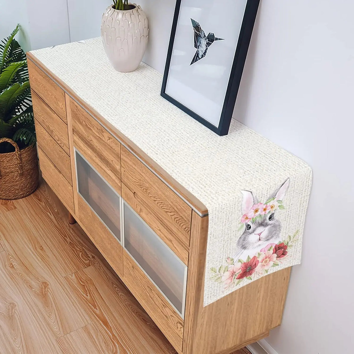 Un meuble de rangement en bois avec des tiroirs et un cadre décoratif sur le dessus, orné d'un lapin mignon au milieu de fleurs roses.