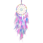 Un attrape-rêves coloré avec des plumes roses, bleues et violettes, suspendu par un fil rose.