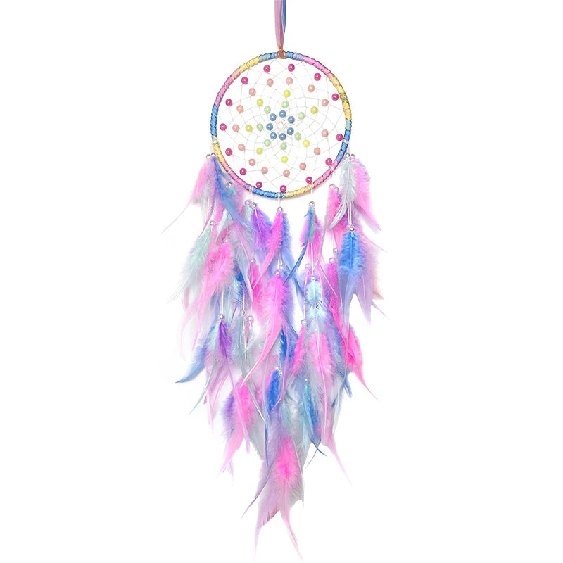 Un attrape-rêves coloré avec des plumes roses, bleues et violettes, suspendu par un fil rose.
