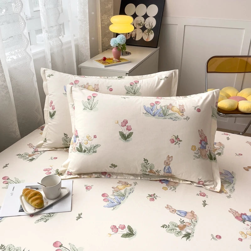 Des coussins aux motifs floraux et de lapins, sur un lit avec une lampe jaune et des éléments de décoration, créant une atmosphère chaleureuse et accueillante dans la pièce.