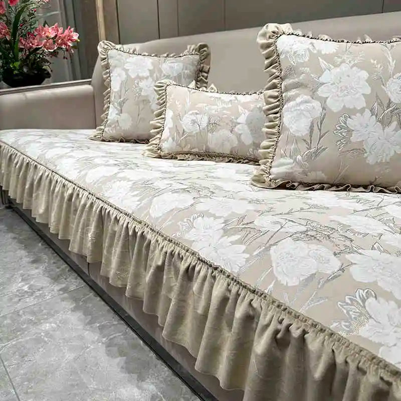 Une élégante salle de repos avec un canapé élégamment décoré de coussins et d'une belle parure de lit florale sur un fond gris neutre.