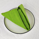 Un chiffon de cuisine vert vif plié sur une assiette ronde noire.