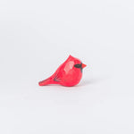 L'image montre une figurine en forme d'oiseau cardinal rouge vif, posée sur un fond blanc, avec des détails fins qui soulignent les plumes et le bec de l'animal.