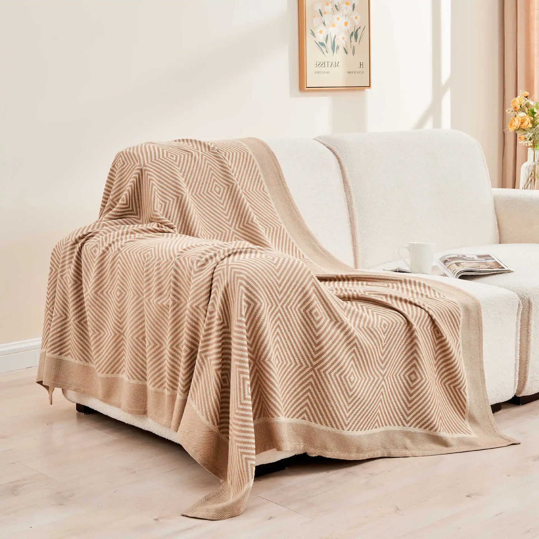 Une couverture en coton beige à motifs géométriques élégants, parfaitement assortie au décor de cette pièce sereine.