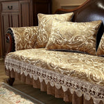 Élégant canapé en bois foncé avec des oreillers et une housse motif baroque or et beige, orné d'une dentelle blanche raffinée sur le pourtour.