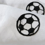 Gros plan sur un motif brodé en forme de ballon de football noir sur un tissu blanc transparent.