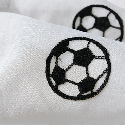Gros plan sur un motif brodé en forme de ballon de football noir sur un tissu blanc transparent.