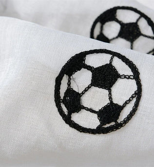 Gros plan sur un motif brodé en forme de ballon de football noir sur un tissu blanc transparent.