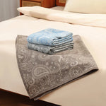 Une pile de serviettes ornées de motifs élégants et paisley, posée sur un lit confortable.