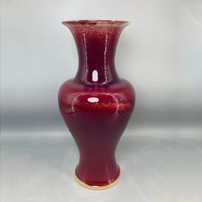 Un vase décoratif en céramique de couleur rouge foncé, avec une finition brillante et un col évasé.