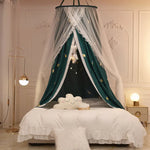 Une belle chambre à coucher avec un ciel de lit décoratif en tissu blanc et vert, rehaussé de motifs étoilés dorés, créant une ambiance chaleureuse et élégante.