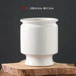 Vase en céramique blanc élégant et simple, avec des lignes épurées et une forme ronde.