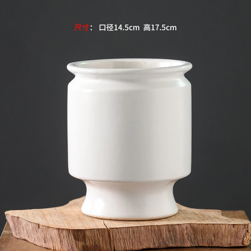 Vase en céramique blanc élégant et simple, avec des lignes épurées et une forme ronde.