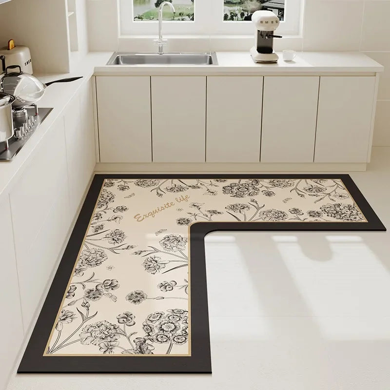 Tapis de cuisine avec motif floral élégant et inscription "Bienvenue" en noir et blanc, placé au sol près d'un évier et de meubles de cuisine blancs.