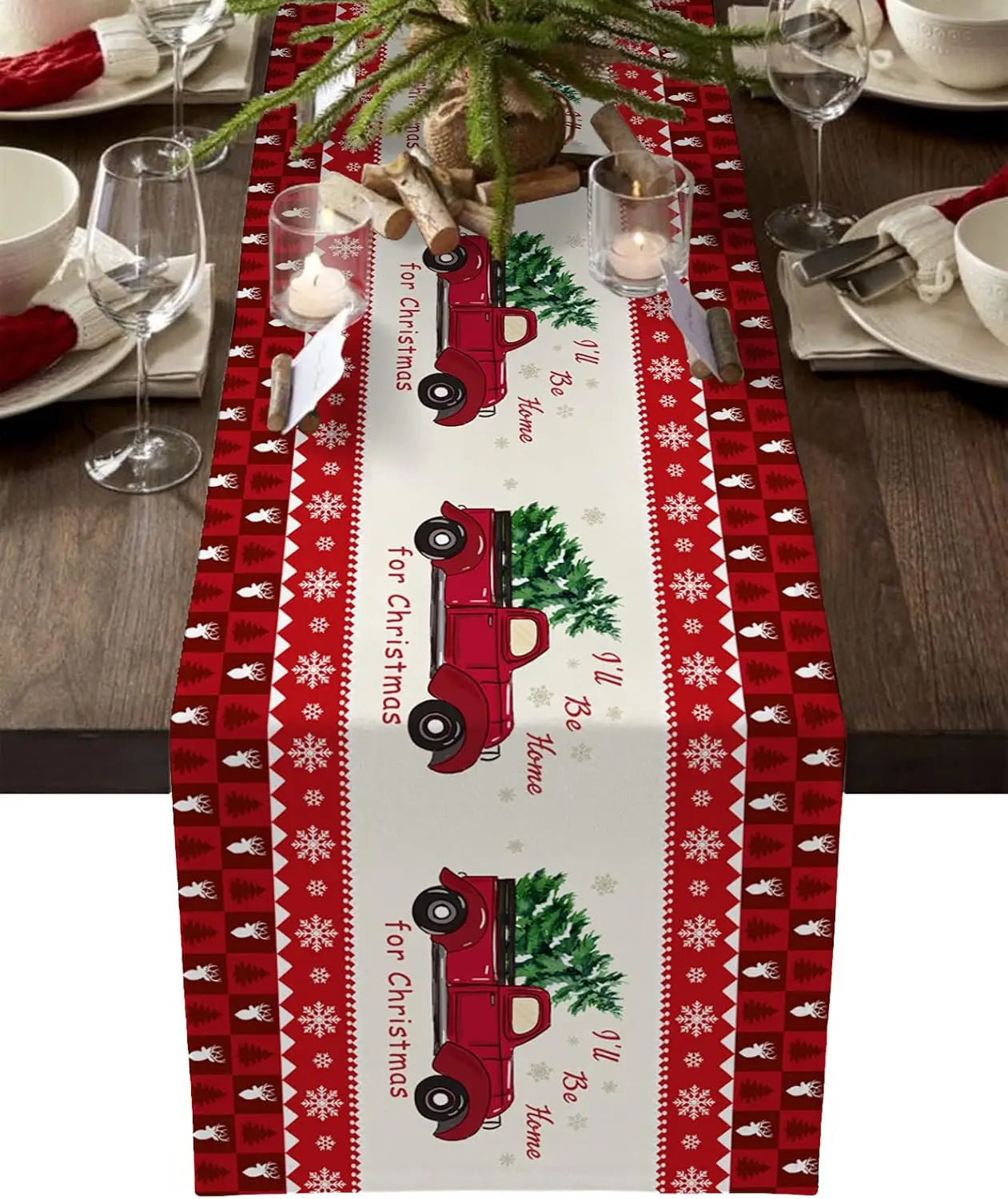 Table de Noël avec une nappe et des décorations de Noël. La nappe présente un motif de flocons de neige et de petits camions rouges avec des arbres de Noël.