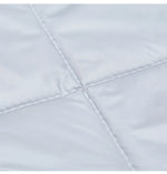 Gros plan du tissu matelassé gris clair du rideau de porte, montrant les coutures en losange et la texture douce et soyeuse.