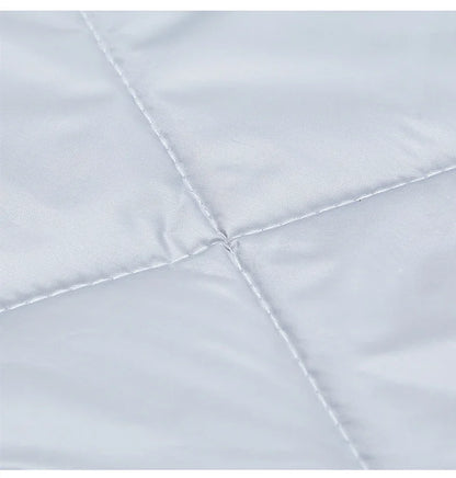 Gros plan du tissu matelassé gris clair du rideau de porte, montrant les coutures en losange et la texture douce et soyeuse.