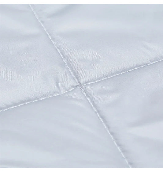 Gros plan du tissu matelassé gris clair du rideau de porte, montrant les coutures en losange et la texture douce et soyeuse.