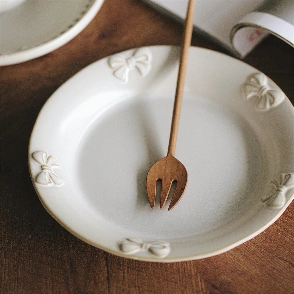 Une assiette en céramique blanche décorée de motifs floraux avec une fourchette en bois posée au centre.