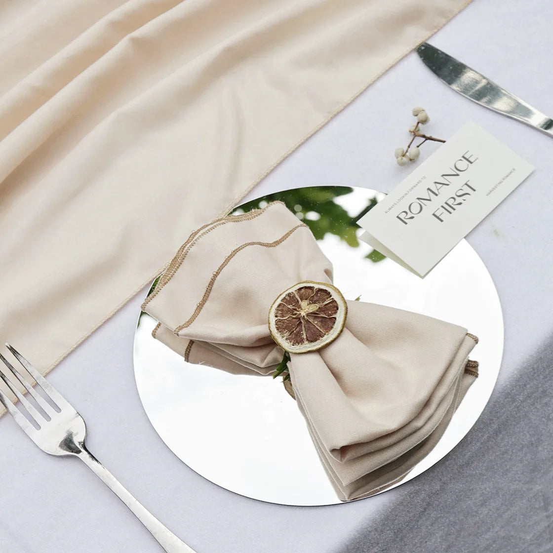 Arrangement de table élégant avec une serviette beige, une tranche de citron et une décoration florale.