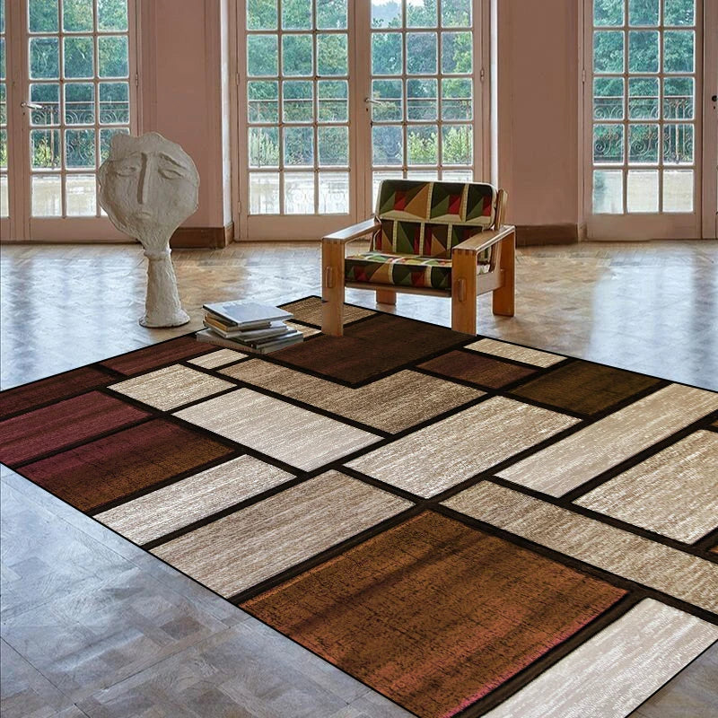 L'image montre un intérieur lumineux avec de grandes fenêtres, un fauteuil en bois et une sculpture sur le sol, avec un tapis coloré et décoratif composé de carrés de différentes nuances.