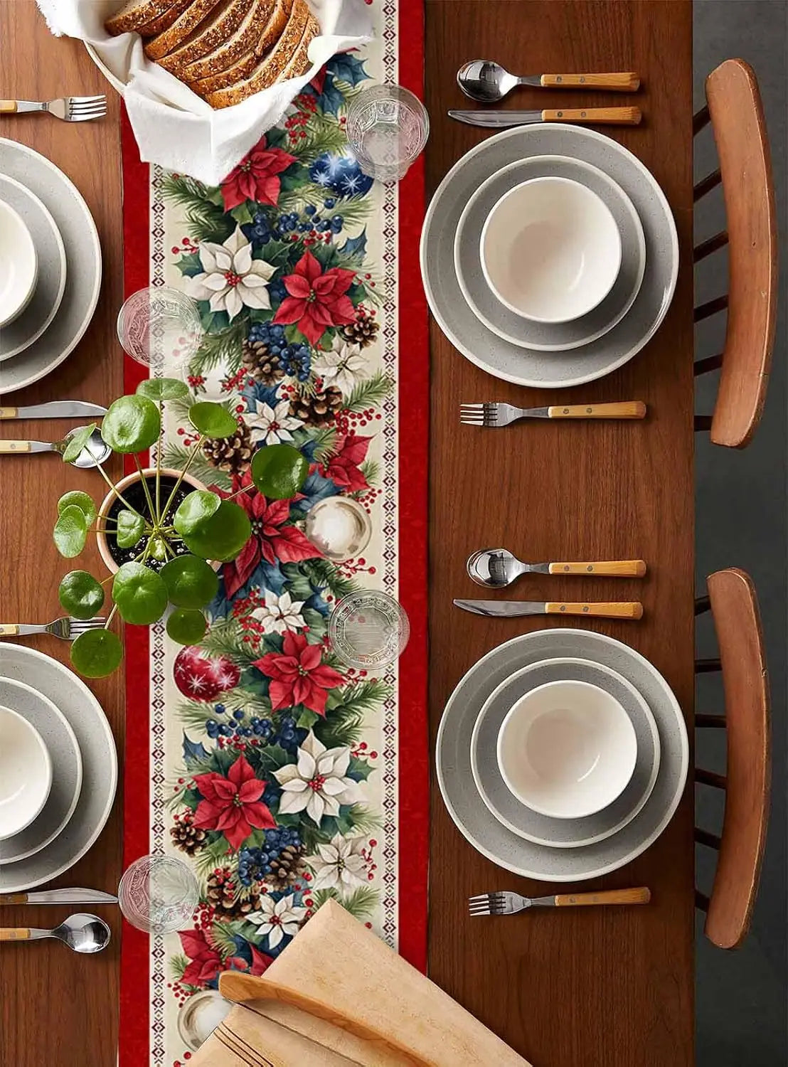 La table est joliment décorée pour une occasion festive, avec des plaques blanches, des couverts en bois et un chemin de table fleuri aux couleurs vives.