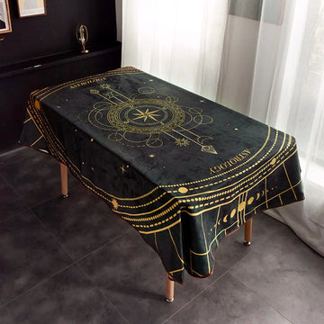 Cette nappe noire et dorée, ornée de motifs astrologiques, crée une ambiance mystique et élégante dans la pièce.