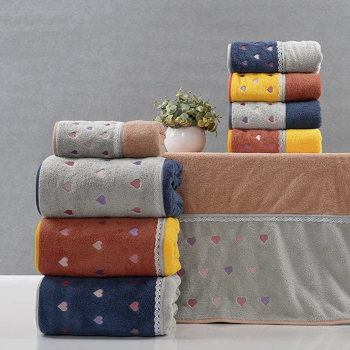 Superbe pile de serviettes de bain douillettes et colorées avec des motifs de cœurs, posées sur une étagère avec un pot de fleurs.