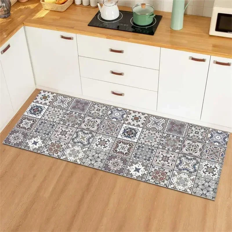 Tapis de cuisine en carreaux de céramique grise avec motifs floraux décoratifs, posé sur un parquet clair dans une cuisine moderne équipée.