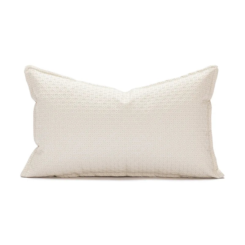 Coussin décoratif blanc texturé avec un motif géométrique subtil.