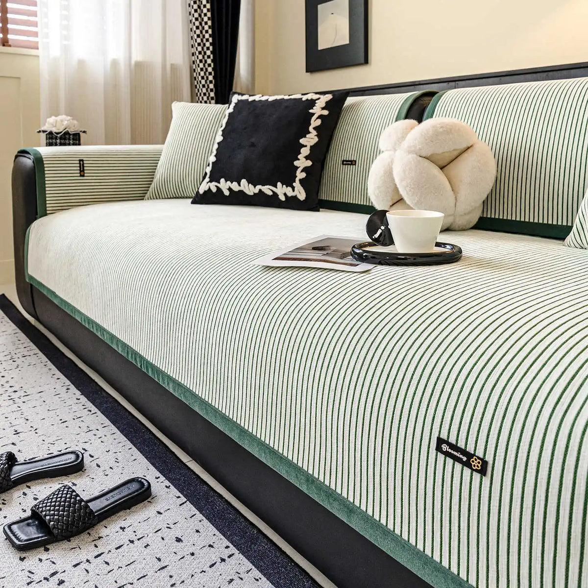 Lit de bois avec une literie rayée noir et blanc, des coussins décoratifs, une tasse de café et un ours en peluche, créant une ambiance confortable et élégante dans cette pièce.