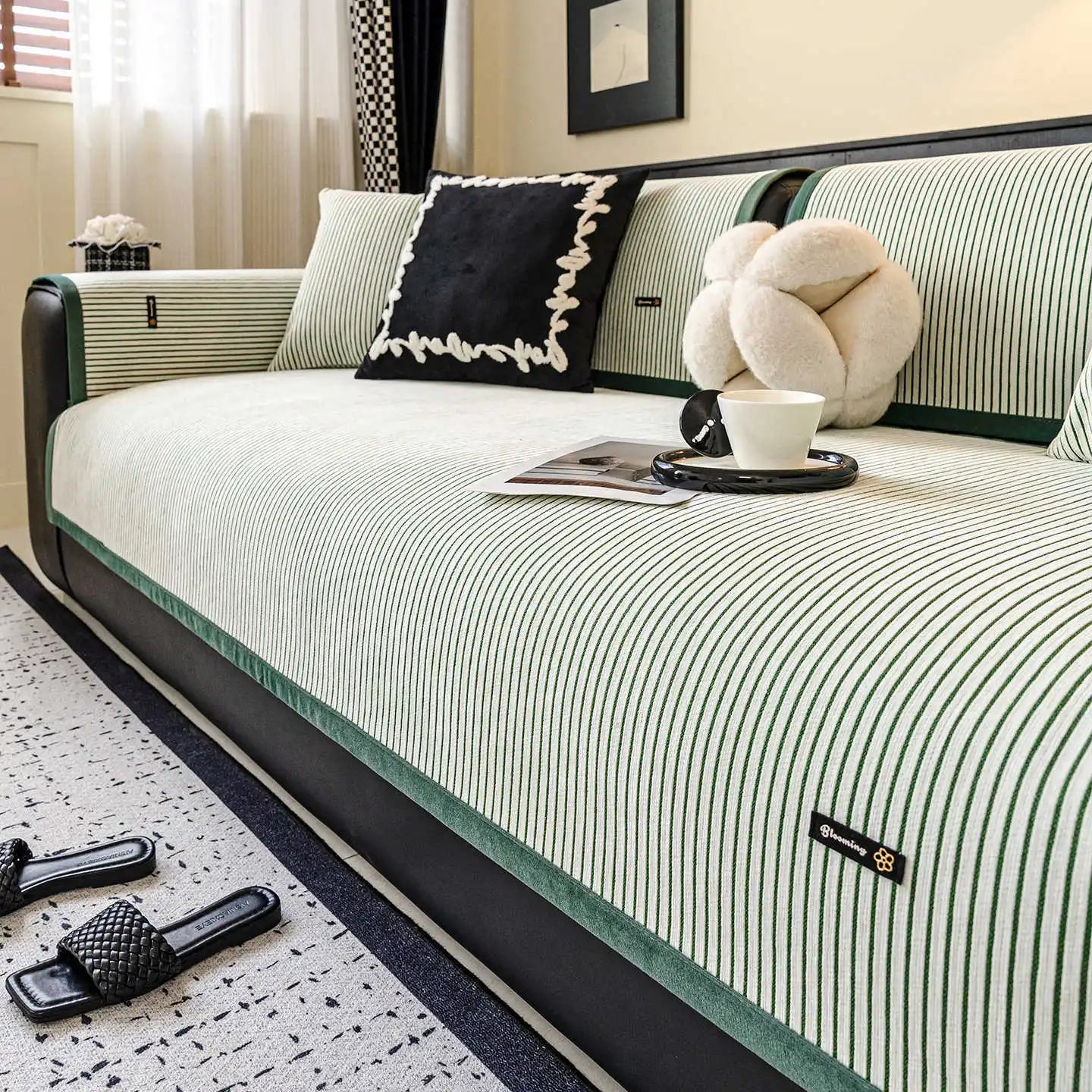 Lit de bois avec une literie rayée noir et blanc, des coussins décoratifs, une tasse de café et un ours en peluche, créant une ambiance confortable et élégante dans cette pièce.